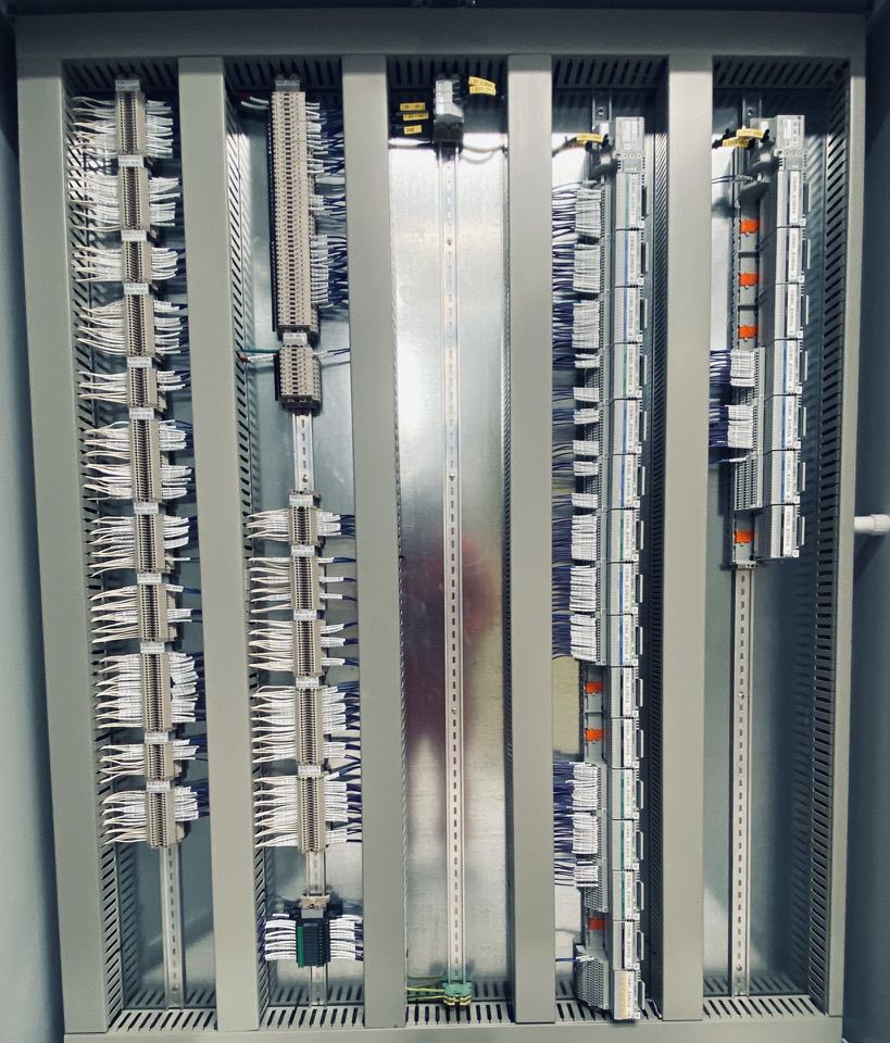 A large grey control panel opened up, with vertical rows of terminal blocks and neat wiring ducts